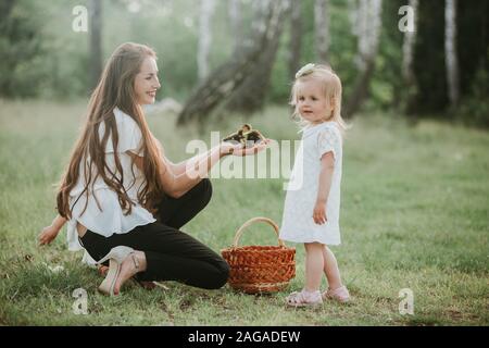 Mère montre des enfants peu de canetons dans panier d'osier. petit canard dans les mains d'une femme. La maman montre à sa fille un petit canard Banque D'Images