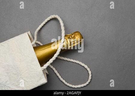 Champagne : Sac cadeau avec une bouteille de vin mousseux à la surface de carreaux gris. Banque D'Images