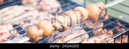 Mettre les champignons sur les brochettes grillés sur charbons. Image avec la profondeur de champ. Banque D'Images