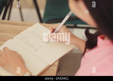 Gros plan grand angle d'une femme prenant des notes dans un ordinateur portable Banque D'Images