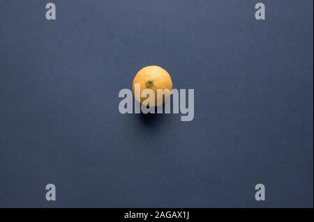 Vue aérienne d'une seule orange sur une surface bleue Banque D'Images