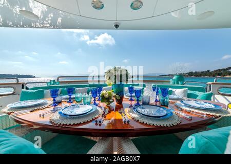 Table sur le thème de l'océan avec assiettes bleues, verres à vin et bouquet de fleurs sur un yacht de luxe Banque D'Images