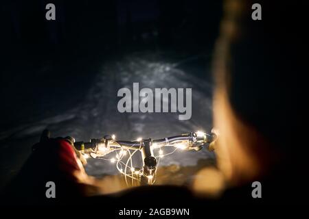 Guidon de vélo de montagne décoré de lumières de Noël à snow road dans au nuit d'hiver Banque D'Images