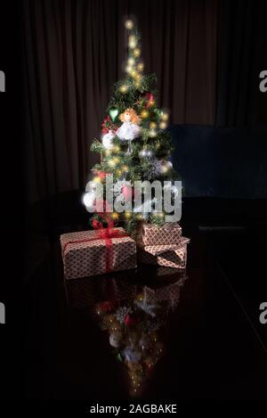 Beau petit et décoré l'arbre de Noël et beaucoup de cadeaux à la maison avec un fond sombre Banque D'Images