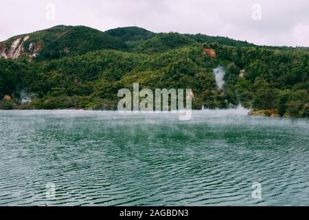 De la vapeur s'échappe d'un beau plan d'eau entouré par des montagnes vertes Banque D'Images