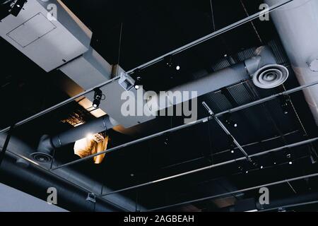 Photo basse angle d'un plafond noir en métal avec du blanc tuyaux de ventilation Banque D'Images