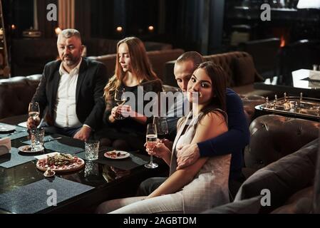 L'homme donne une accolade à une fille. Amis de la famille avoir beau temps dans un beau restaurant moderne de luxe Banque D'Images