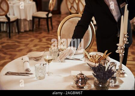 Serveur professionnel la préparation de la table dans le restaurant de style vintage luxure Banque D'Images