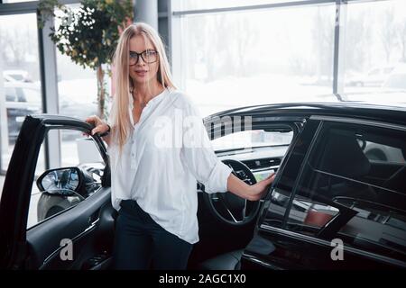 À partir de l'automobile. Photo en mouvement. Girl a testé sa nouvelle voiture noire. Dirait qu'elle a convaincu Banque D'Images