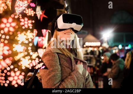 Belle femme profitant de l'atmosphère imaginaire avec des lunettes VR arrière-plan flou Banque D'Images