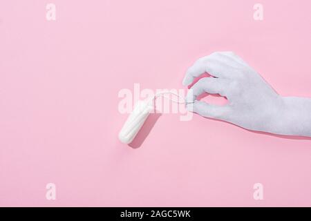 Vue de dessus du white paper cut hand holding tampon de coton sur fond rose Banque D'Images