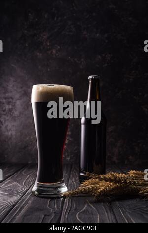 Bouteille et verre de bière de blé près de crampons sur table en bois Banque D'Images