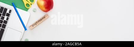 Ordinateur portable, de bloc en bois avec inscription septembre, apple, ciseaux, crayon feutre, papier vert isolated on white Banque D'Images