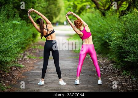 La remise en forme. Deux dames qui s'étend à l'extérieur dans les jambes en été Banque D'Images