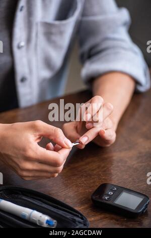 Portrait de femme de sang près de moniteur de glucose à la maison Banque D'Images