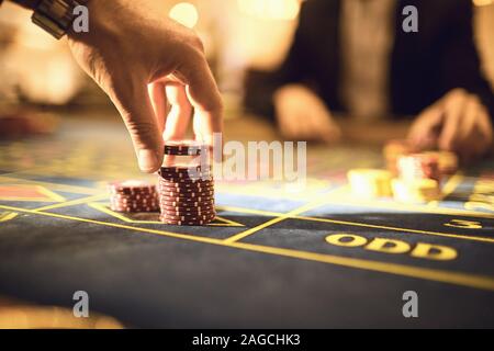 Les joueurs à la main faire des paris de jetons pour jouer à la roulette dans un casino Banque D'Images