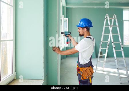 Constructeur travailleur installe des cloisons sèches à une construction de plâtre Banque D'Images