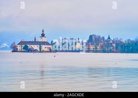 Promenade le long du lac Traunsee brumeux avec vue sur Schloss Ort (Orth) château, situé sur la petite île et les Alpes autour d'elle, Gmunden, Salzkam Banque D'Images