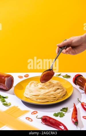 Portrait de femme d'ajouter le ketchup à surface blanche sur spaghetti isolé sur le jaune Banque D'Images