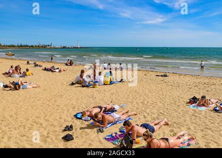 Les personnes bénéficiant de soleil à la plage St Kilda, la plage la plus célèbre de Melbourne, Australie Banque D'Images