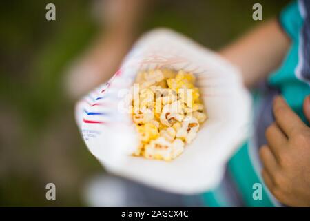 Photo en grand angle d'une personne tenant un sac en papier avec pop-corn Banque D'Images