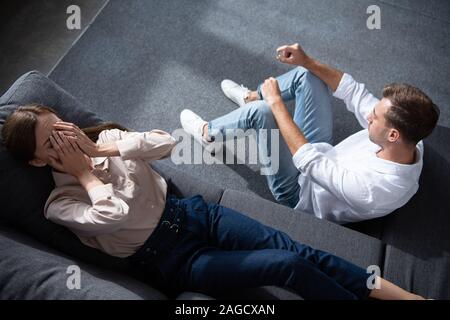 Vue de dessus de pleurer bouleversée woman on sofa et man sitting on floor in living room Banque D'Images