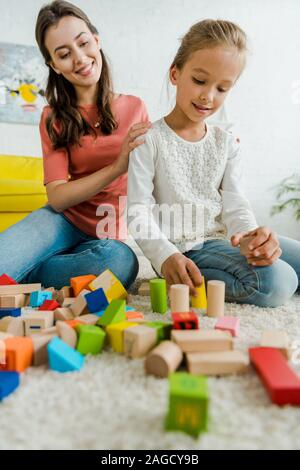 Focus sélectif de kid Playing with toy blocks près de cheerful baby-sitter Banque D'Images