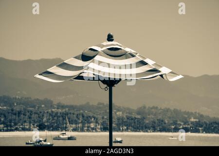 Un gros plan d'une plage à rayures ou parasol de terrasse avec un fond de voiliers dans le port de Santa Barbara avec en sépia, Santa Barbara, CA Banque D'Images