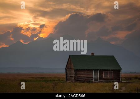 Décor mignon du soleil se coucher sur une maison de campagne au milieu d'une ferme Banque D'Images