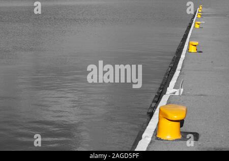 L'eau du port de l'image monochrome et une partie de requête avec bollards jaune pour les bateaux comme arrière-plan with copy space Banque D'Images