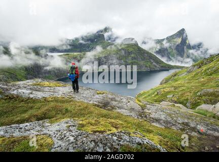 Randonneur se tenant à côté d'un lac dans les montagnes Lofoten une journée brumeuse Banque D'Images