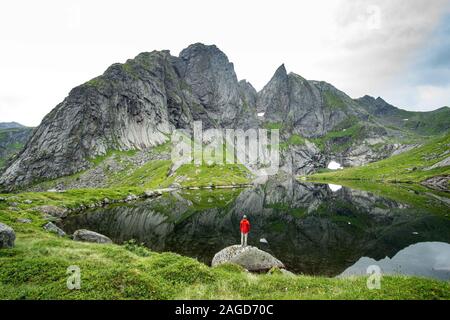 Homme debout à côté d'un lac dans les montagnes Lofoten une journée brumeuse Banque D'Images