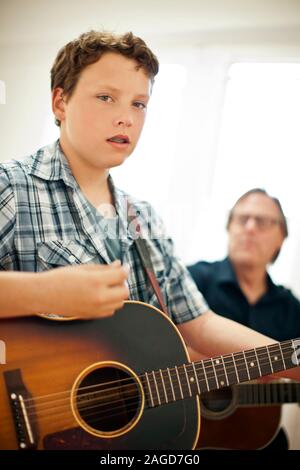 Teenage boy and girl playing acoustic guitars Banque D'Images