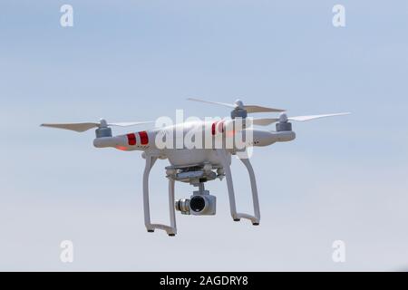 Bourdon blanc dans le ciel bleu - un drone DJI Phantom Standard avec l'appareil photo sur le vol planant dans la tourelle. Banque D'Images