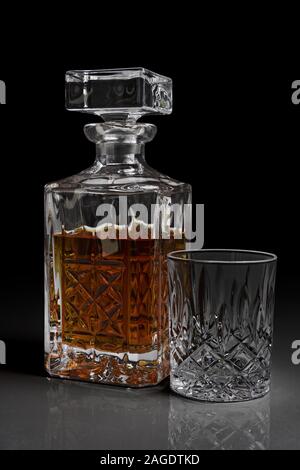 Plan vertical d'une bouteille de whisky en verre antique et d'un verre avec fond noir Banque D'Images