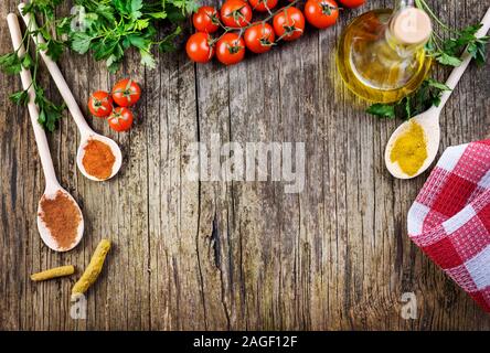 Vue de dessus de divers ingrédients alimentaires sur vintage table en bois. Mélanger les épices, tomate cerise, d'herbes et d'huile d'olive sur fond rustique à partir de ci-dessus. La cuisson Banque D'Images