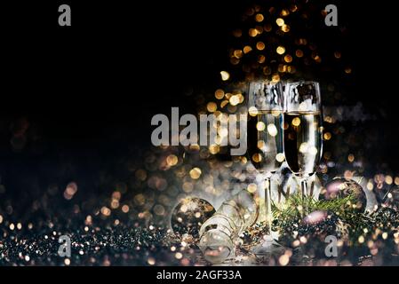 Deux verres de champagne et décoration de Noël sur fond d'Or foncé effet bokeh. Nouvel an et célébration de Noël parti de luxe. Nouvelle année Banque D'Images