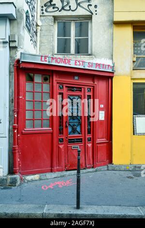 Une ancienne porte d'entrée rouge, avec des graffitis dans la rue Charlot, une rue dans le quartier historique du Marais dans le 3ème arrondissement, Paris, France Banque D'Images