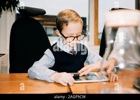 Jeune garçon travaillant avec son père à son bureau Banque D'Images