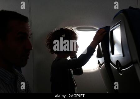 Petit garçon assis sur l'avion à regarder un film Banque D'Images