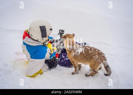 Young male snowboarder joue avec les chiots dans une station de ski en hiver Banque D'Images