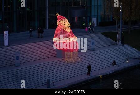 Wolfsburg, Allemagne. Dec 18, 2019. Un énorme Père Noël lumineux se trouve dans l'Autostadt sur la rive de la Canal Mittelland. En moins d'une semaine, ce sera la veille de Noël. Credit : Friso Gentsch/dpa/Alamy Live News Banque D'Images