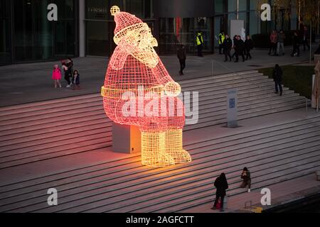 Wolfsburg, Allemagne. Dec 18, 2019. Un énorme Père Noël lumineux se trouve dans l'Autostadt sur la rive de la Canal Mittelland. En moins d'une semaine, ce sera la veille de Noël. Credit : Friso Gentsch/dpa/Alamy Live News Banque D'Images