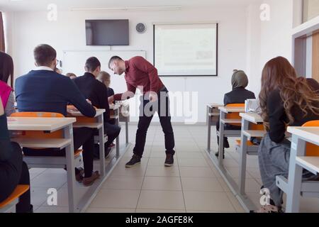 Le professeur mâle leçon expliquer aux élèves et à interagir avec eux dans la salle de classe.Aider les étudiants pendant un cours. Être aidés par des étudiants de l'université Banque D'Images