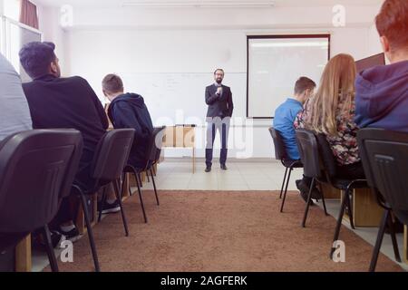 Le professeur mâle leçon expliquer aux élèves et à interagir avec eux dans la salle de classe.Aider les étudiants pendant un cours. Banque D'Images