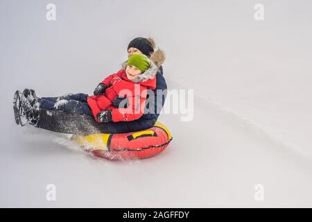 Maman fils monter sur une luge hiver gonflable tube. Plaisir d'hiver pour toute la famille Banque D'Images