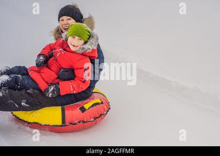 Maman fils monter sur une luge hiver gonflable tube. Plaisir d'hiver pour toute la famille Banque D'Images