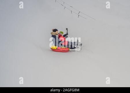 Maman fils monter sur une luge hiver gonflable tube. Plaisir d'hiver pour toute la famille Banque D'Images