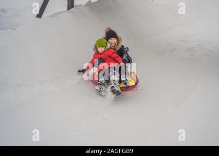 Maman fils monter sur une luge hiver gonflable tube. Plaisir d'hiver pour toute la famille Banque D'Images