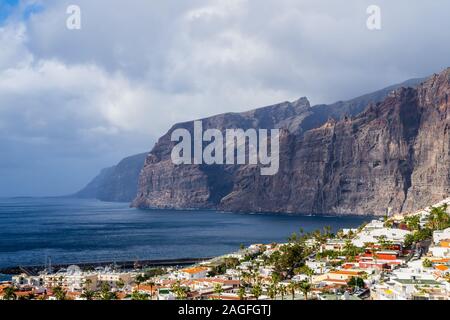 Espagne, Ténérife, belle vue aérienne au-dessus de maisons de ville côtière célèbre à côté de falaises géant appelé los Gigantes avec nuages de pluie Banque D'Images